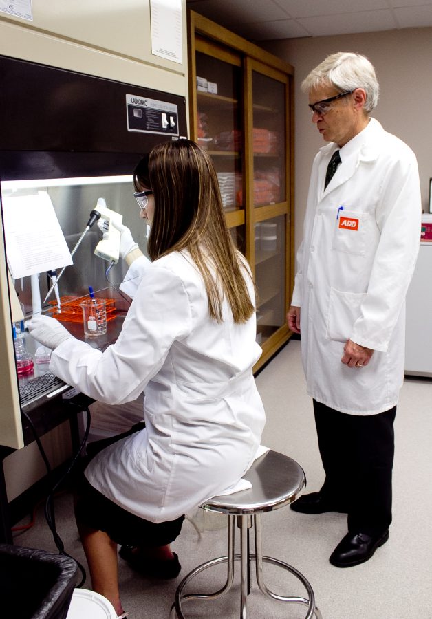 Dr. Steve Figard assists a student as she works in the cancer research lab. Photo: Stephanie Greenwood
