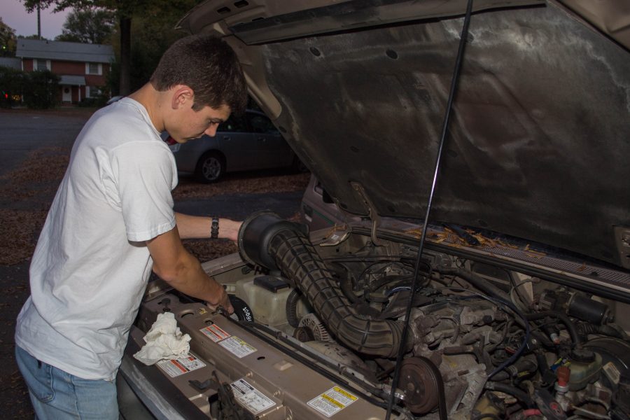 Junior Zack Larsen checks under the hood of his car in preparation for his trip back home to Maryland. Photo: Jacob Larsen