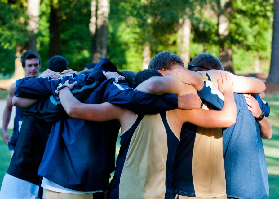 The men’s cross country team pauses to pray before running their inaugural meet. Photo: Molly Waits