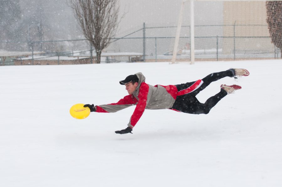 Taking a dive in the snow, a student lunges to catch a Frisbee on a snow-covered soccer field.    Photo: Molly Waits
