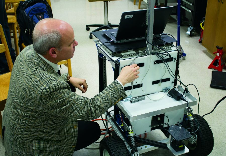 Dr. Bill Lovegrove checks students’ work on this year’s robot for the Intelligent Ground Vehicle Competition.  Photo: Ethan Rogers