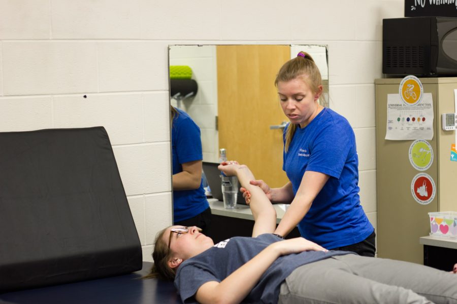 Taylor Wilson stretching athletes’ muscles in preparation for a game to prevent injury.    Photo: Daniel Quigley