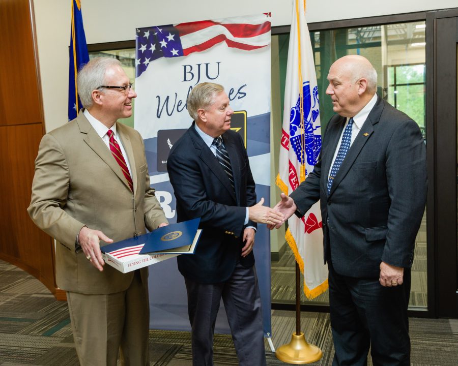 Senitor Lindsey Graham presents a US Flag to BJU president, Steve Pettit, and Commander Al Carper to welcome ROTC to BJU, Greenville, SC, April 4, 2018. (Hal Cook)