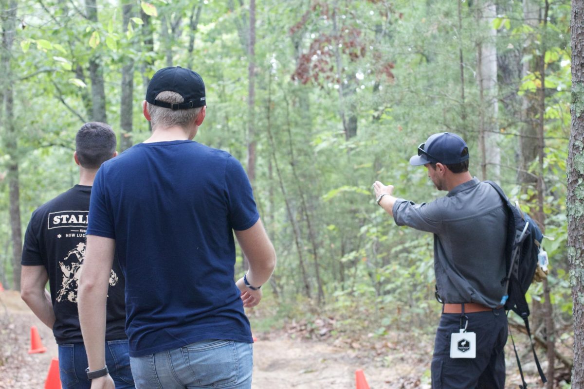 Trail guide explaining course to Andrew Dubberly, a senior business administration major, and Holden Weisbecker, a junior business administration major.