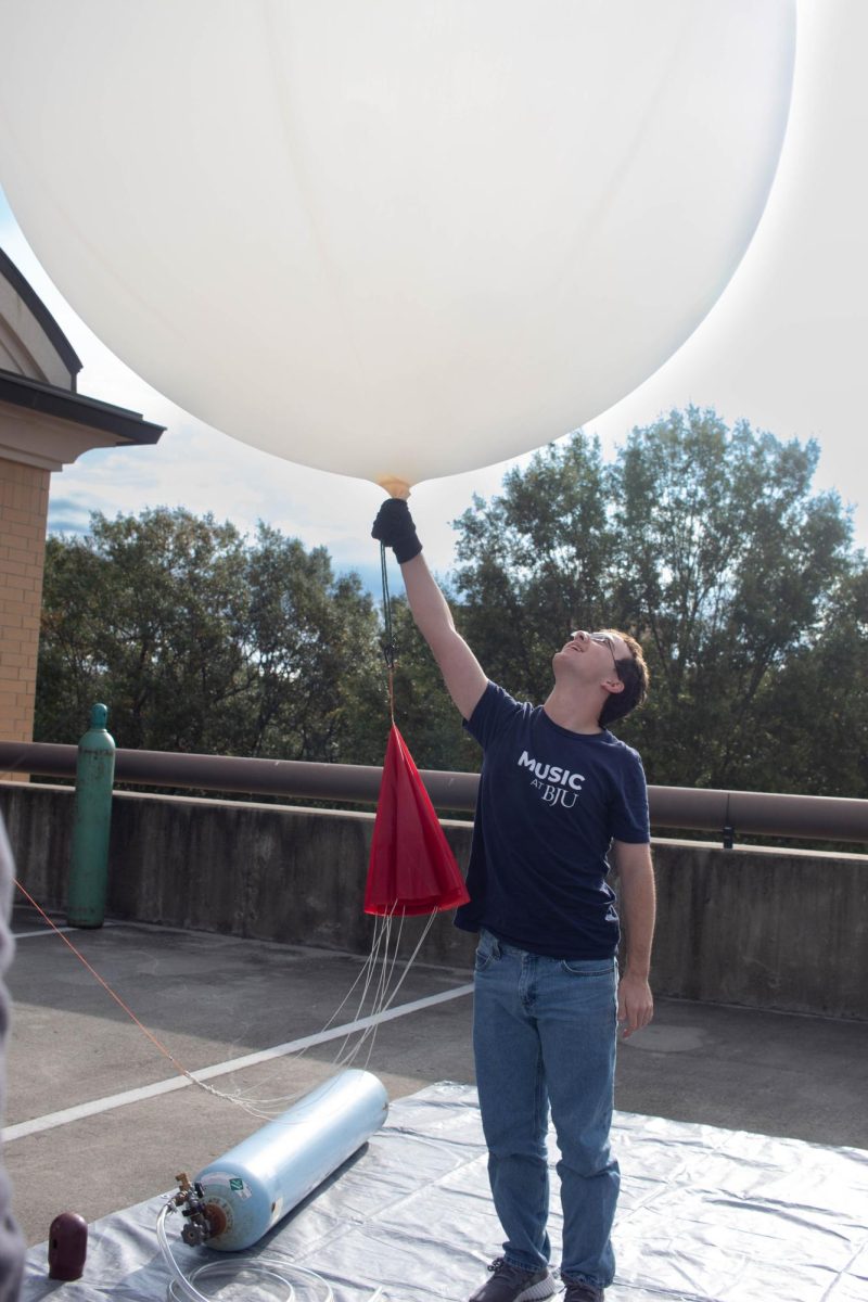 Student holds a weather balloon down.