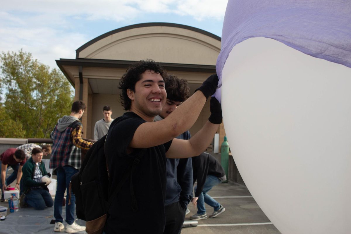 A student holds down the balloon with a sheet to get an accurate weight of the balloon.