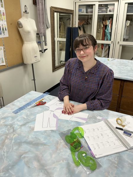 Olivia Crute, a fashion design major, poses with her materials in the Sargent Art Building.