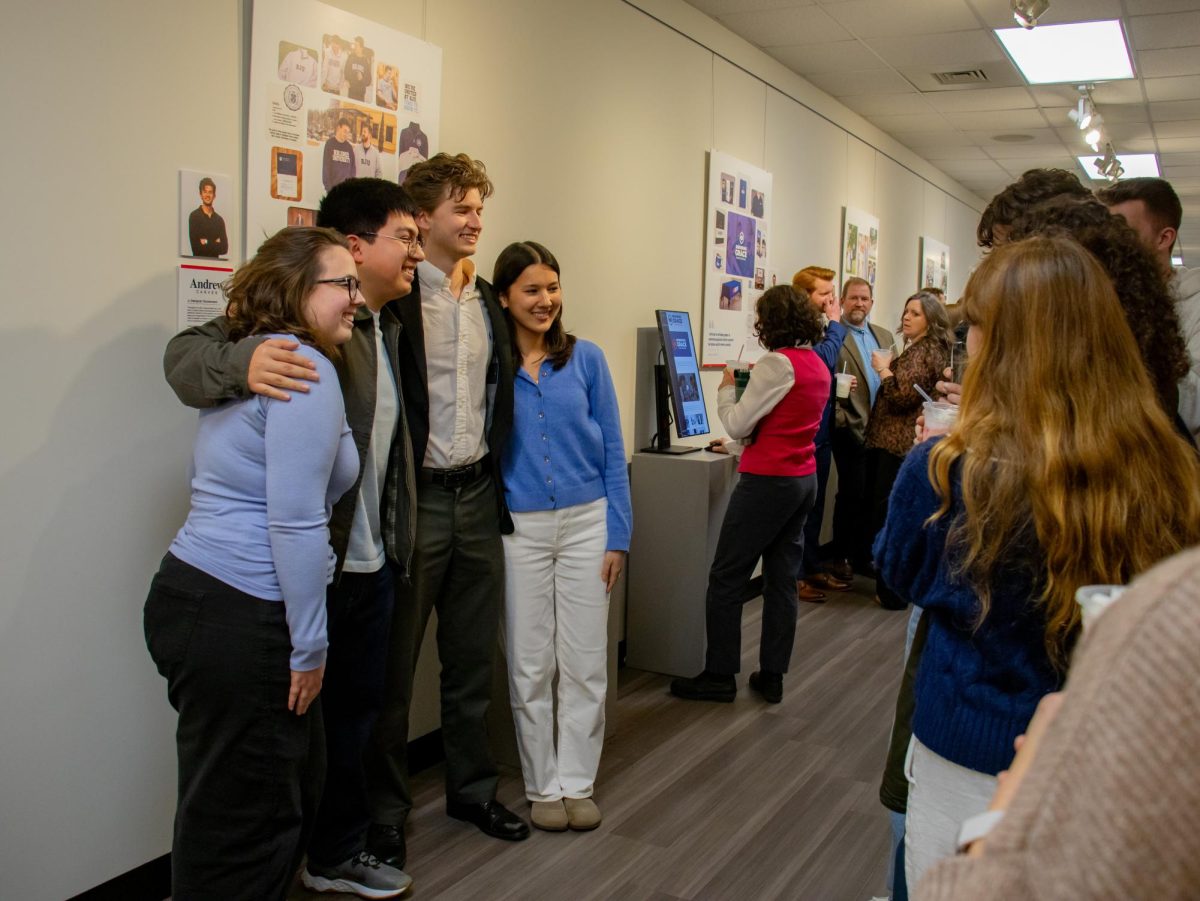 Andrew Carver takes photos with friends at his graphic design portfolio presentation.